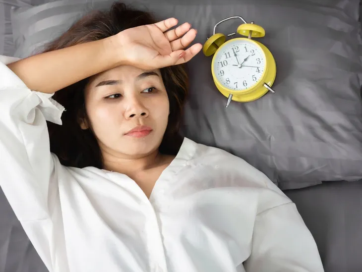 Woman lying awake at night overthinking and worrying about worst-case scenarios